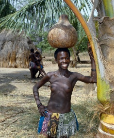 Kenya, Malindi, Gongoni. A Giriama girl from Kenyas Coast Province carrying a gourd full of water on her head. Her small skirt is made from strips of printed cotton material.